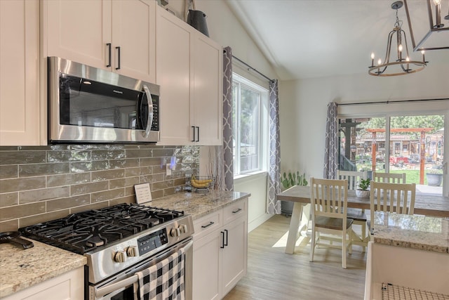 25523 N N Sheridan Rd, Chattaroy, WA 99003 - kitchen with stainless steel appliances, vaulted ceiling, backsplash, a chandelier, and light wood-style flooring
