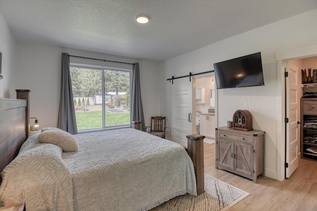 25523 N N Sheridan Rd, Chattaroy, WA 99003 - bedroom featuring a barn door, light wood-type flooring, and connected bathroom