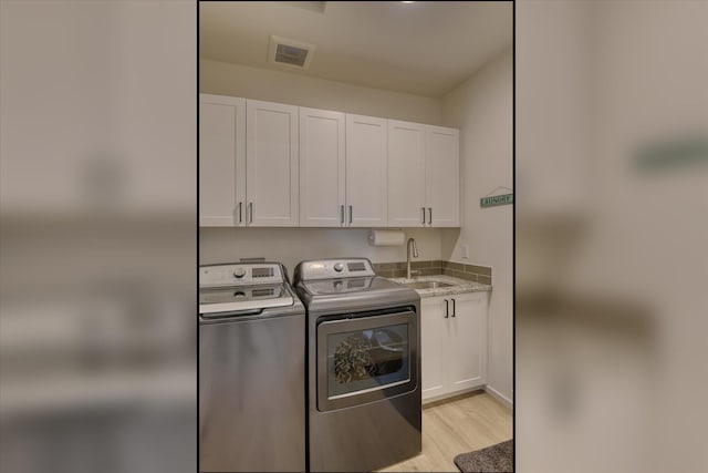 25523 N N Sheridan Rd, Chattaroy, WA 99003 - laundry area featuring cabinet space, washing machine and clothes dryer, and light wood-style flooring