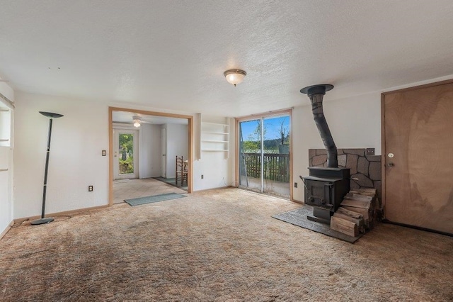 47 Davis Lake Ln, Usk, WA 99180 - unfurnished living room featuring a wood stove, carpet floors, and a textured ceiling