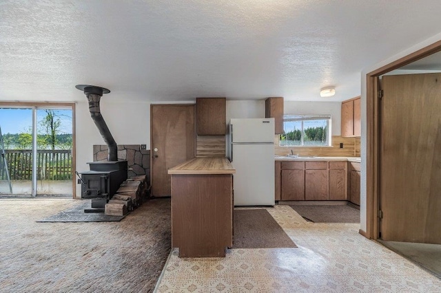 47 Davis Lake Ln, Usk, WA 99180 - kitchen featuring freestanding refrigerator, a wood stove, a textured ceiling, light countertops, and a sink