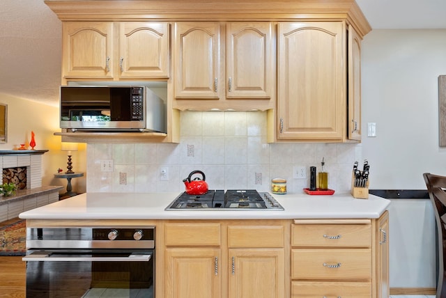 kitchen with appliances with stainless steel finishes, light brown cabinetry, light countertops, and tasteful backsplash