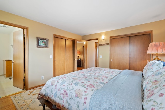bedroom featuring multiple closets, light wood-type flooring, and baseboards