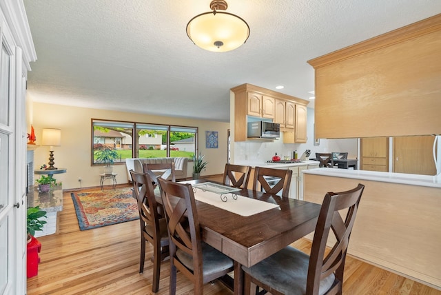 dining room featuring light wood-type flooring, a textured ceiling, and recessed lighting