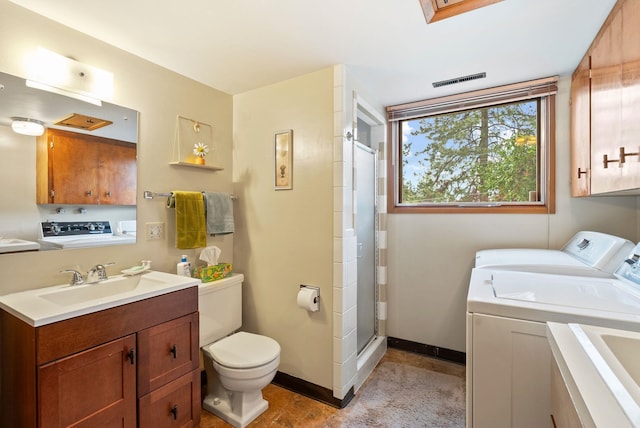bathroom featuring washer and dryer, toilet, a stall shower, vanity, and baseboards