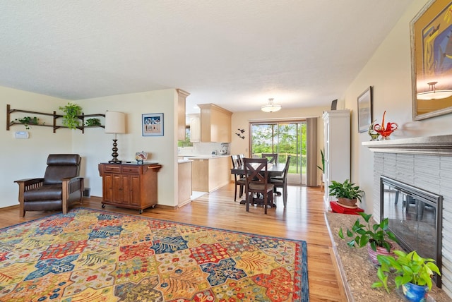 living area with light wood-style flooring and a brick fireplace