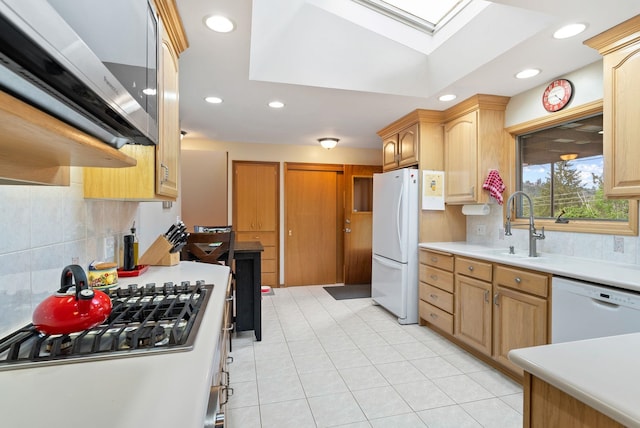 kitchen featuring white appliances, a skylight, a sink, tasteful backsplash, and recessed lighting