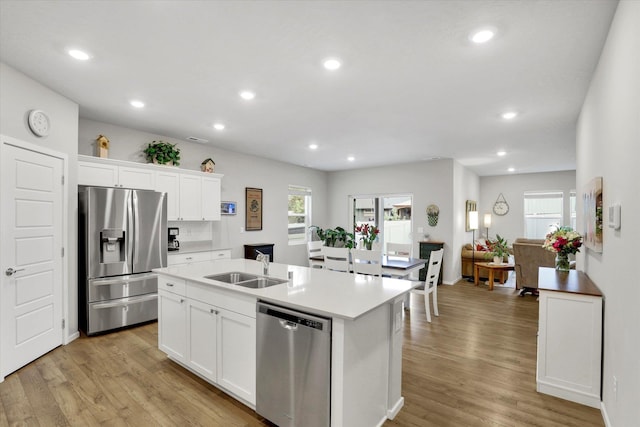 5704 W Jamestown Ln, Spokane, WA 99208 - kitchen with appliances with stainless steel finishes, a sink, light wood-style floors, a kitchen island with sink, and white cabinets