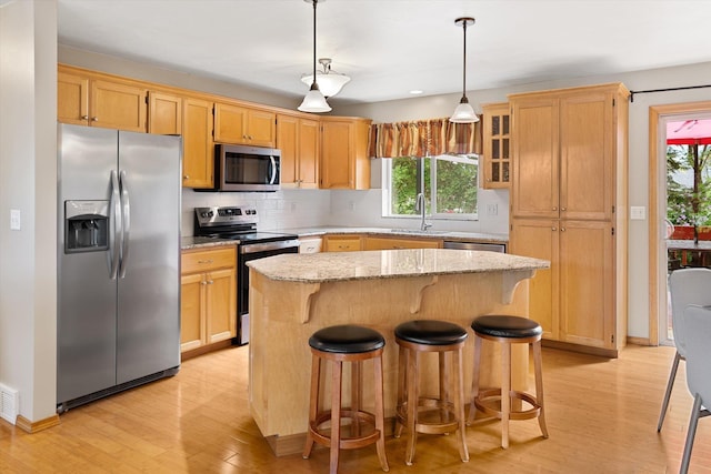 5229 S Altamont Ln, Spokane, WA 99223 - kitchen with appliances with stainless steel finishes, light wood-style floors, a center island, tasteful backsplash, and light stone counters