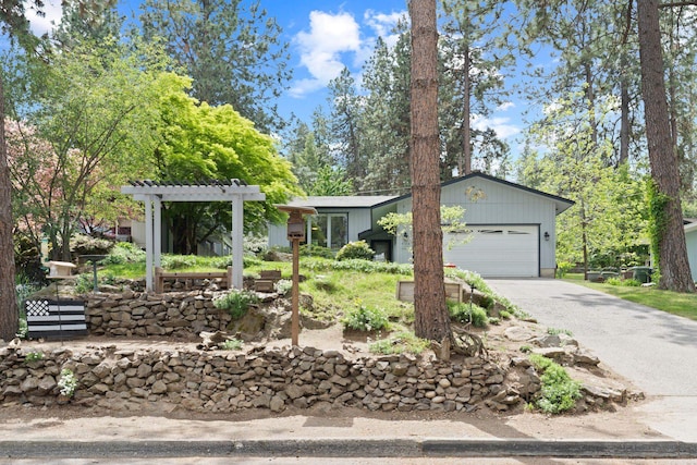 ranch-style home with driveway, an attached garage, and a pergola