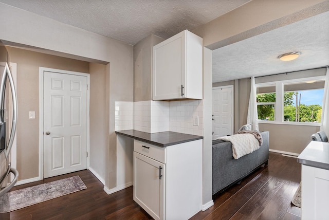 3214 E 29th Ave, Spokane, WA 99223 - kitchen with dark wood-style floors, a textured ceiling, white cabinetry, tasteful backsplash, and baseboards