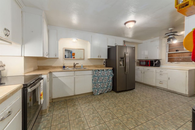 kitchen featuring stainless steel appliances, a sink, light countertops, white cabinets, and a ceiling fan