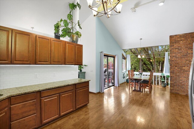 7101 N Greenwood Pl, Spokane, WA 99208 - kitchen with a chandelier, high vaulted ceiling, plenty of natural light, tasteful backsplash, and dark wood-type flooring