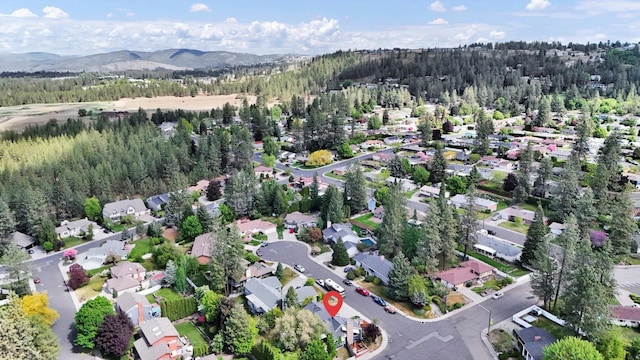 7101 N Greenwood Pl, Spokane, WA 99208 - aerial view of property's location featuring nearby suburban area, a heavily wooded area, and a mountain backdrop