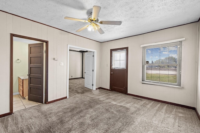 entryway with light carpet, ceiling fan, baseboards, and a textured ceiling
