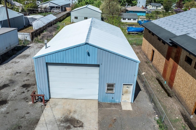 detached garage with concrete driveway, fence, and a residential view
