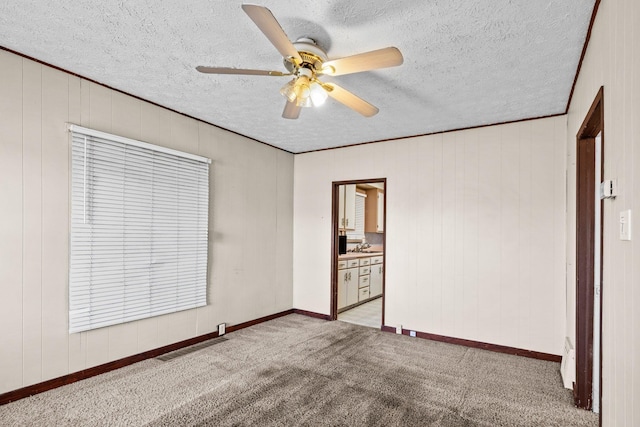 unfurnished bedroom featuring carpet floors, a textured ceiling, ceiling fan, baseboards, and connected bathroom