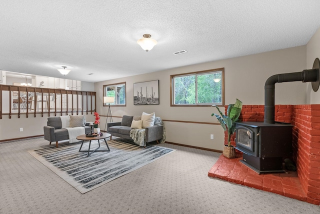 carpeted living area with a wood stove, baseboards, and a textured ceiling