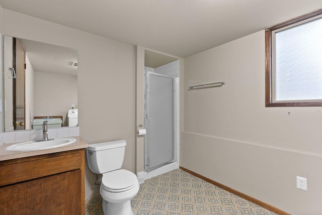 bathroom featuring vanity, toilet, a stall shower, and baseboards