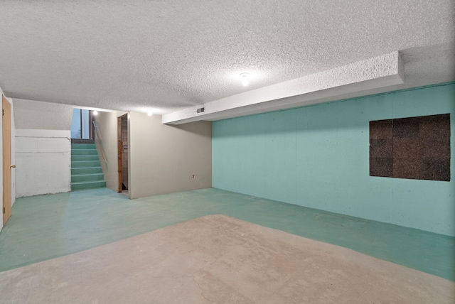 finished below grade area with stairs and a textured ceiling