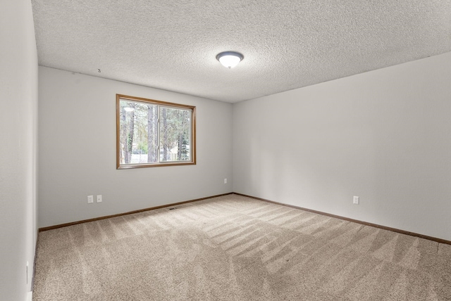 carpeted empty room featuring a textured ceiling and baseboards