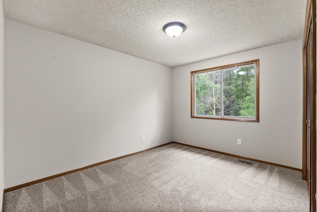 unfurnished room with carpet floors, a textured ceiling, and baseboards