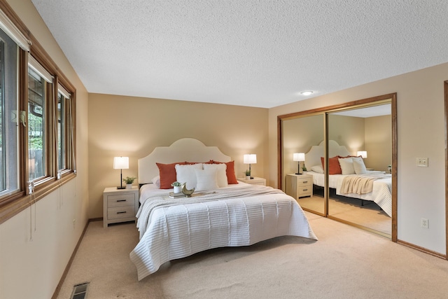 bedroom with light carpet, a textured ceiling, a closet, and baseboards