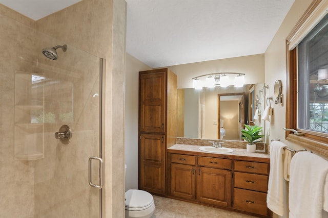 ensuite bathroom with a shower stall, toilet, vanity, and tile patterned floors