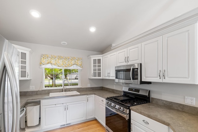 2450 E Black Forest Ave, Post Falls, ID 83854 - kitchen featuring stainless steel appliances, a sink, lofted ceiling, white cabinets, and glass insert cabinets