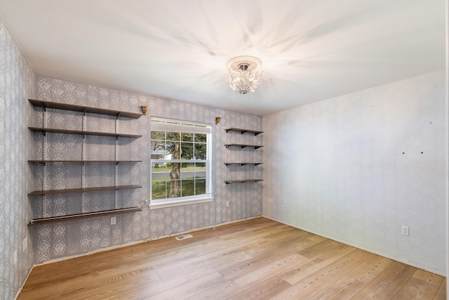 2450 E Black Forest Ave, Post Falls, ID 83854 - spare room with wallpapered walls, wood finished floors, a chandelier, and baseboards