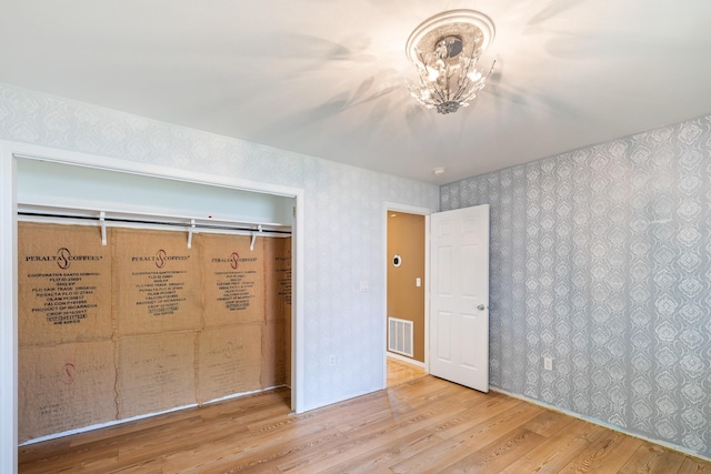 2450 E Black Forest Ave, Post Falls, ID 83854 - unfurnished bedroom featuring wood finished floors, wallpapered walls, and a chandelier