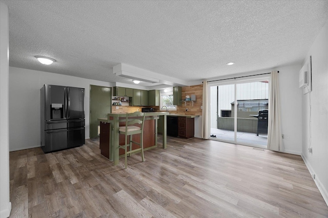 2623 W Olympic Ave, Spokane, WA 99205 - kitchen featuring black fridge, green cabinetry, a textured ceiling, light wood-style floors, and a wall unit AC