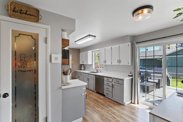 1007 S Bowdish Rd, Spokane Valley, WA 99206 - kitchen with stainless steel dishwasher, a sink, gray cabinetry, light wood-style flooring, and tasteful backsplash