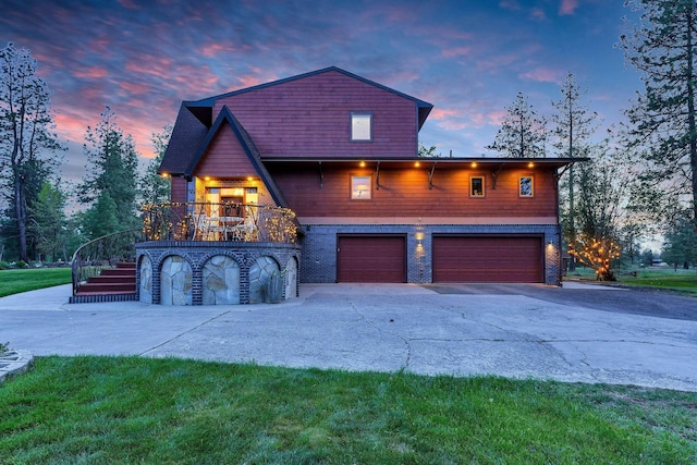 16615 W Stoughton Rd, Cheney, WA 99004 - property exterior at dusk with stairway, driveway, an attached garage, a lawn, and a balcony