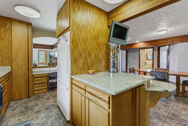 16615 W Stoughton Rd, Cheney, WA 99004 - kitchen with freestanding refrigerator, light stone countertops, a textured ceiling, brown cabinets, and a kitchen island