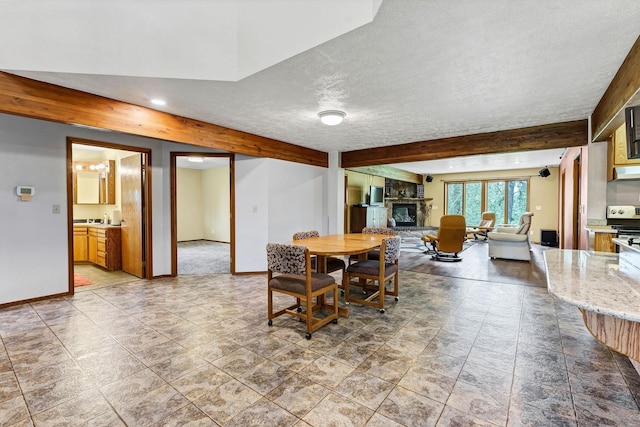 16615 W Stoughton Rd, Cheney, WA 99004 - dining area featuring beamed ceiling, a fireplace, baseboards, a textured ceiling, and recessed lighting