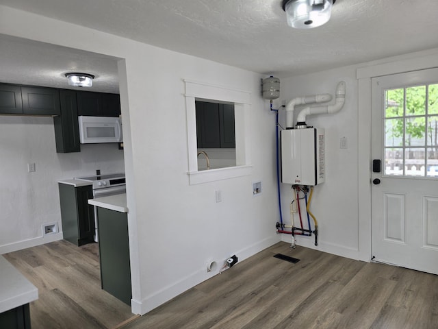3019 E Augusta Ave, Spokane, WA 99207 - laundry area with wood finished floors, a textured ceiling, baseboards, cabinet space, and water heater