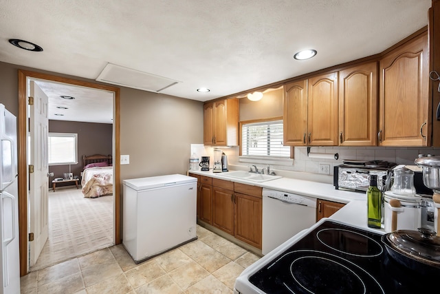 kitchen featuring white appliances, a sink, light countertops, brown cabinets, and recessed lighting