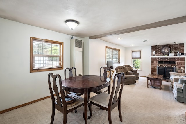 dining space with light colored carpet, a heating unit, a fireplace, baseboards, and beam ceiling