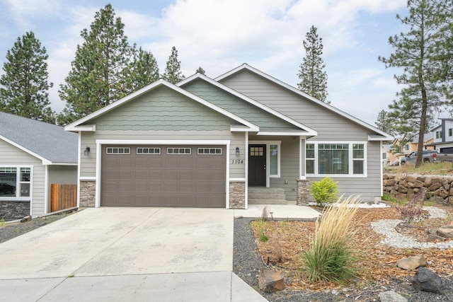 view of front of home with stone siding, a garage, and driveway