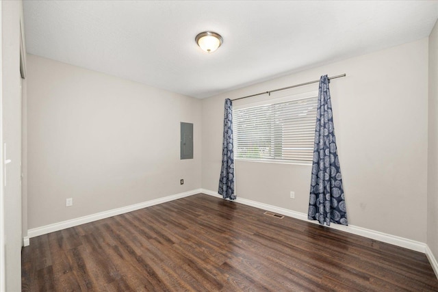 spare room featuring electric panel, wood finished floors, and baseboards