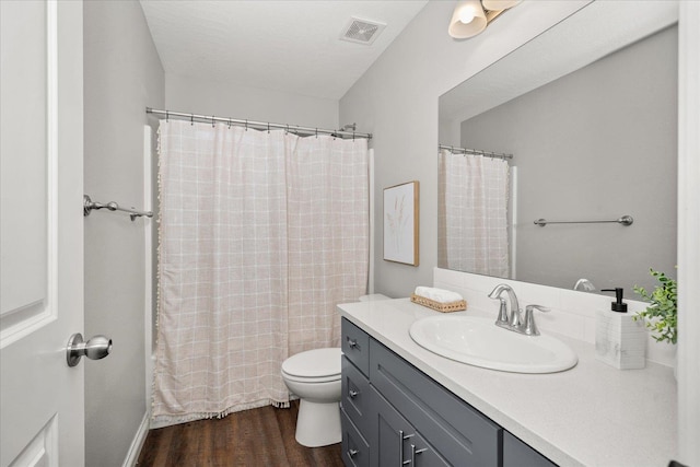 bathroom with wood finished floors, toilet, vanity, and curtained shower