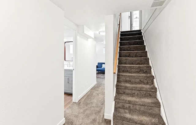 staircase featuring baseboards and carpet