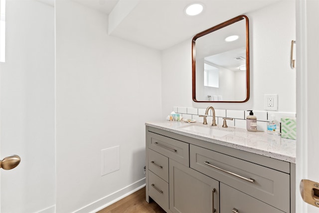 bathroom with wood finished floors, vanity, baseboards, and recessed lighting