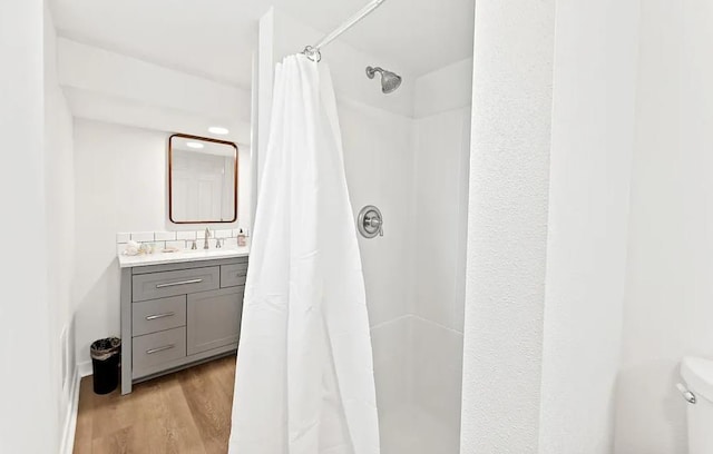 full bath featuring wood finished floors, a shower with curtain, vanity, and toilet