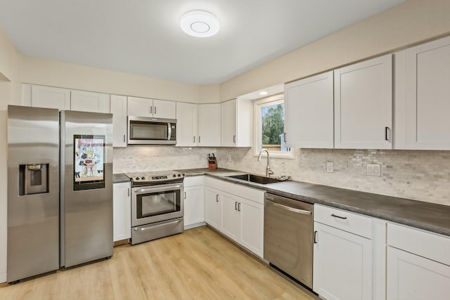13513 E 12th Ave, Spokane Valley, WA 99216 - kitchen with stainless steel appliances, a sink, dark countertops, white cabinets, and light wood-style flooring