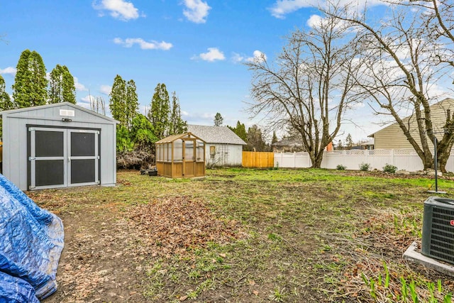 13513 E 12th Ave, Spokane Valley, WA 99216 - view of yard with a greenhouse, an outbuilding, fence, a storage unit, and central AC unit