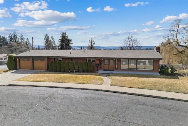 2311 W Wedgewood Ave, Spokane, WA 99208 - ranch-style house with an attached garage, concrete driveway, a chimney, and covered porch