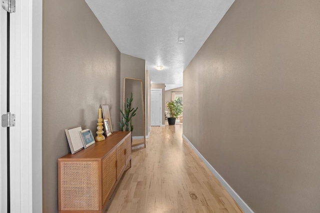 hall featuring light wood-style floors and baseboards