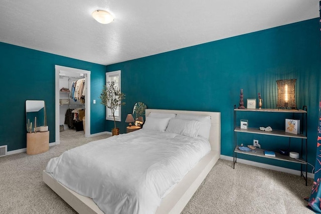 bedroom with carpet floors, a walk in closet, a closet, and baseboards